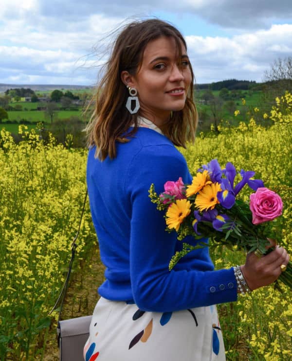 Person wearing a blue jumper, standing in a field of flowers