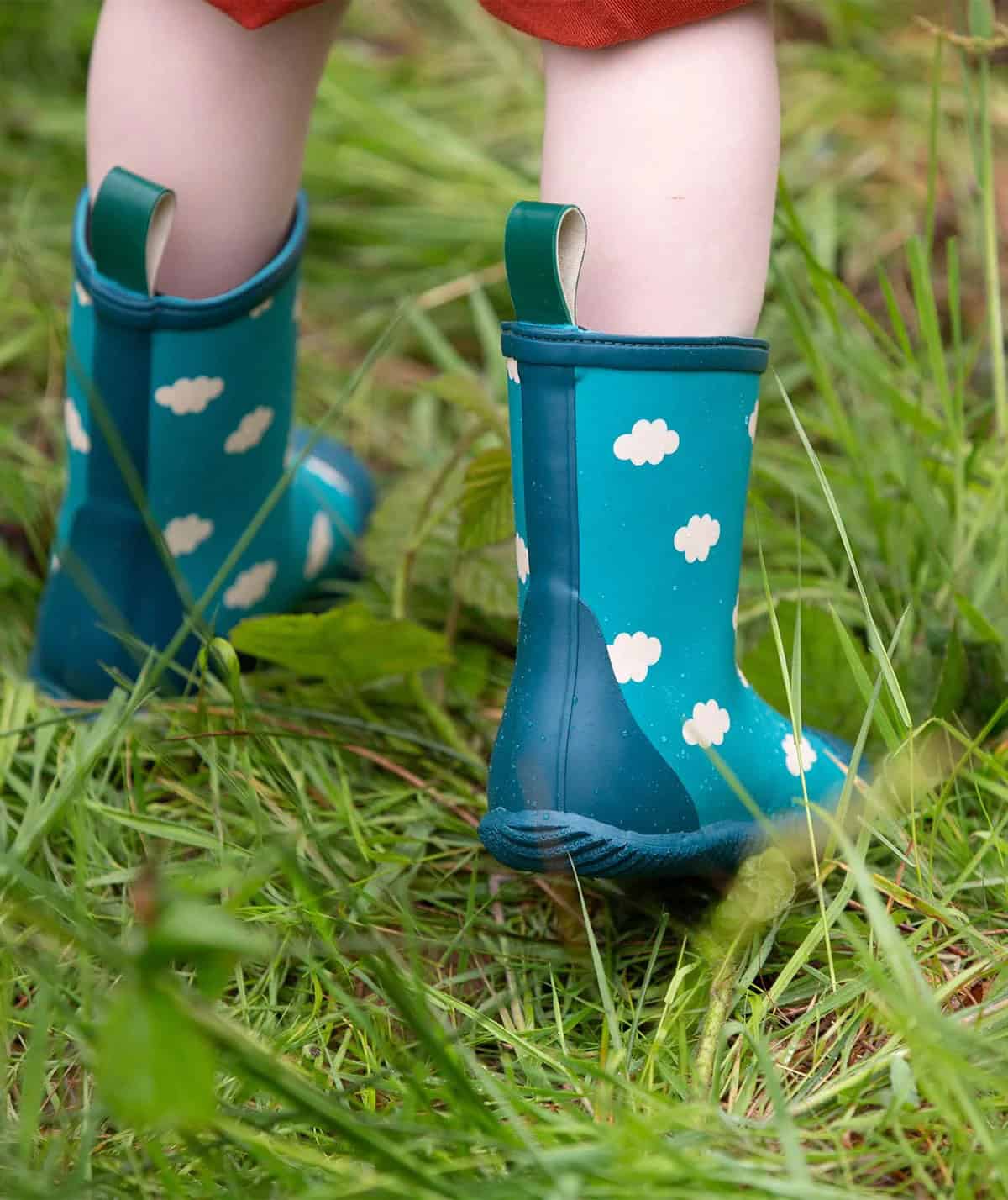 Child wearing green cloud print wellies from sustainable brand Little Green Radicals.