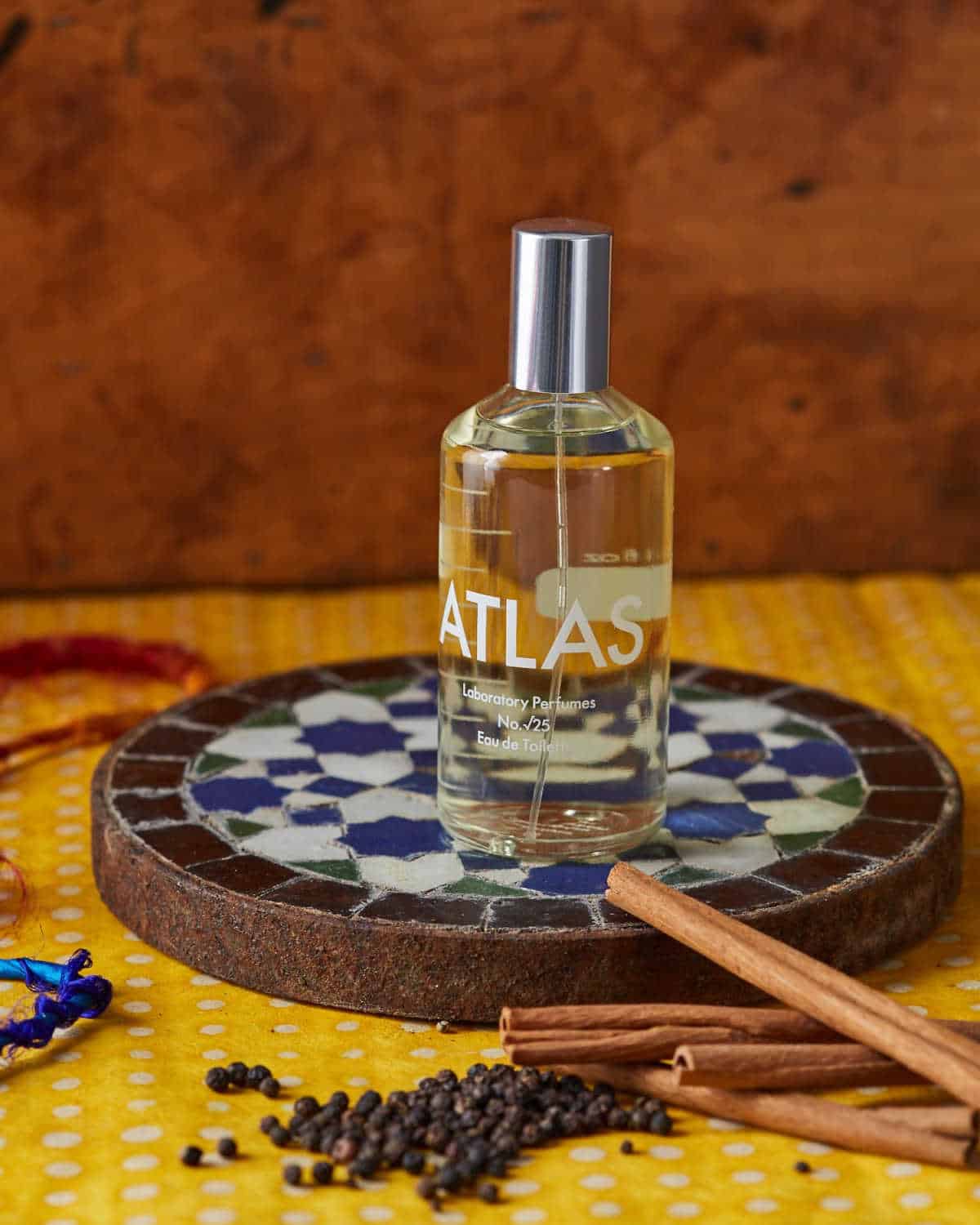 Bottle of Atlas aftershave on a a tiled tray next to various dried herbs.