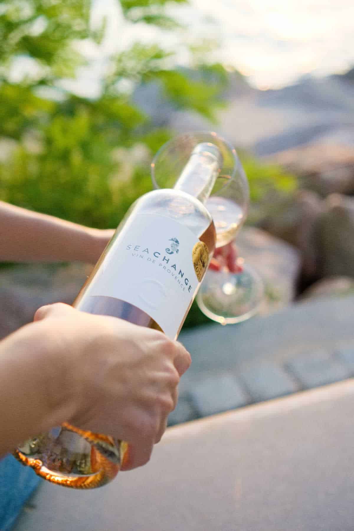 Person pouring a glass of organic prosecco from Seachange, outdoors.