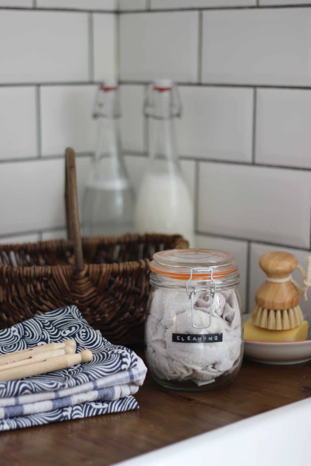 Jar of homemade cleaning wipes, next to a basket, and cloths.