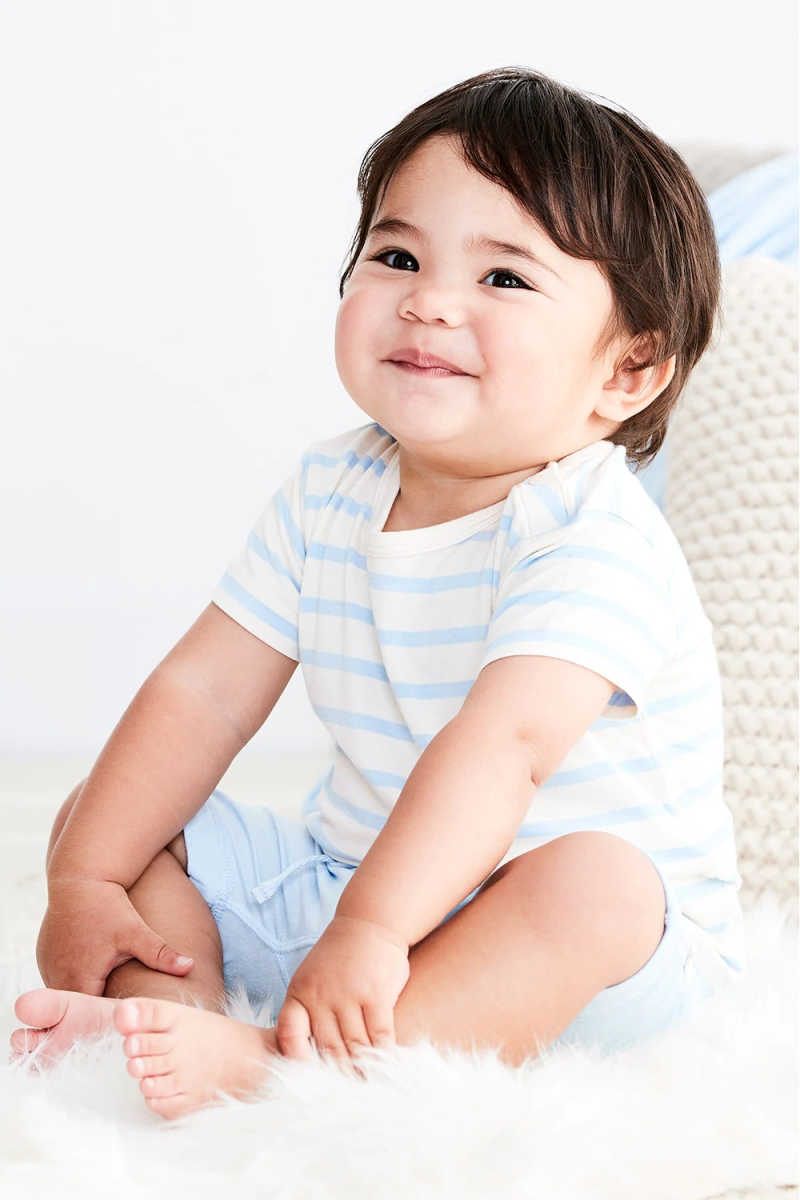 Baby wearing blue striped Boody clothes.