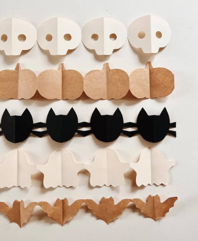 Halloween paper garlands in spooky shapes including skulls, pumpkins, black cats, ghosts and bats.