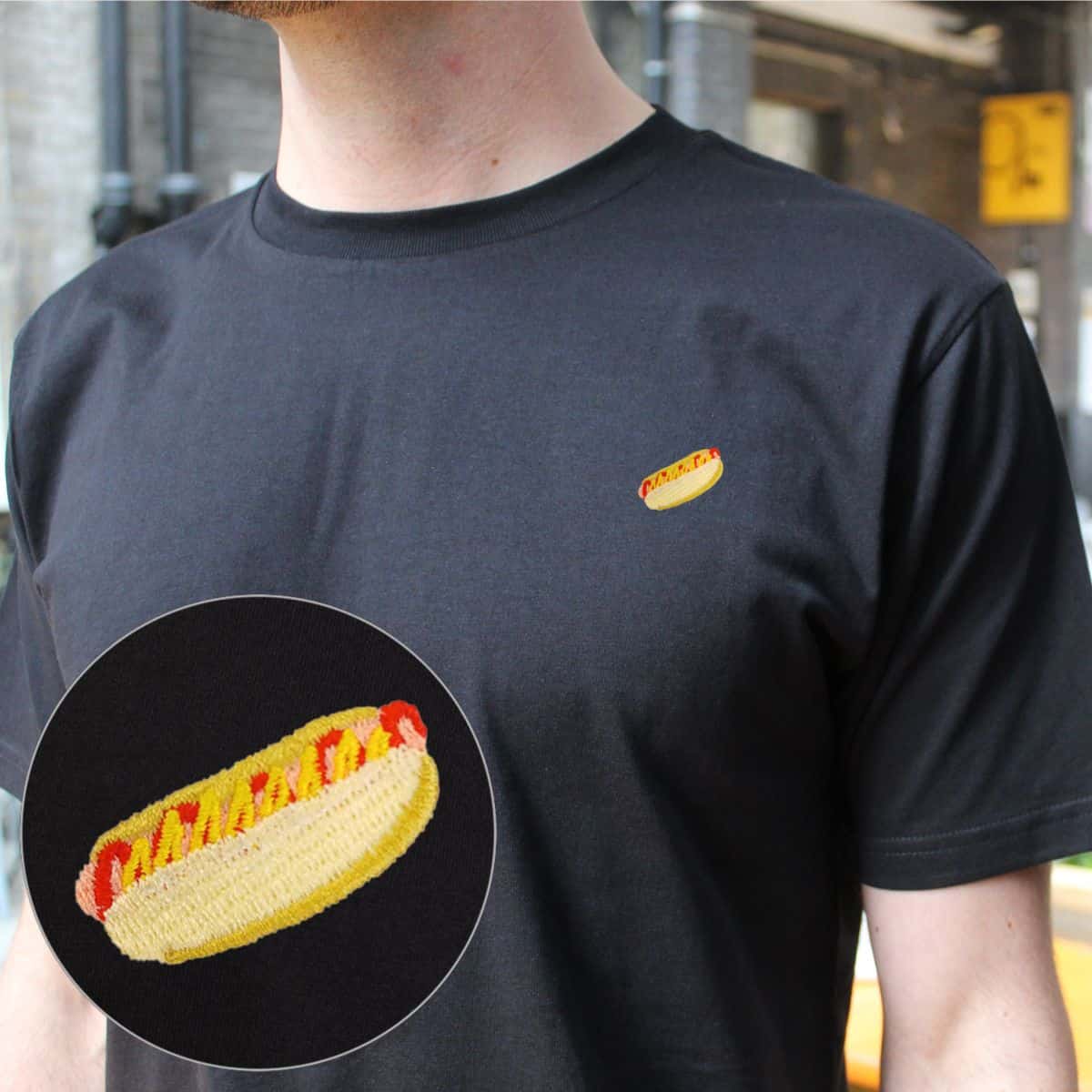 Person wearing a black t-shirt with a hotdog embroidered on it