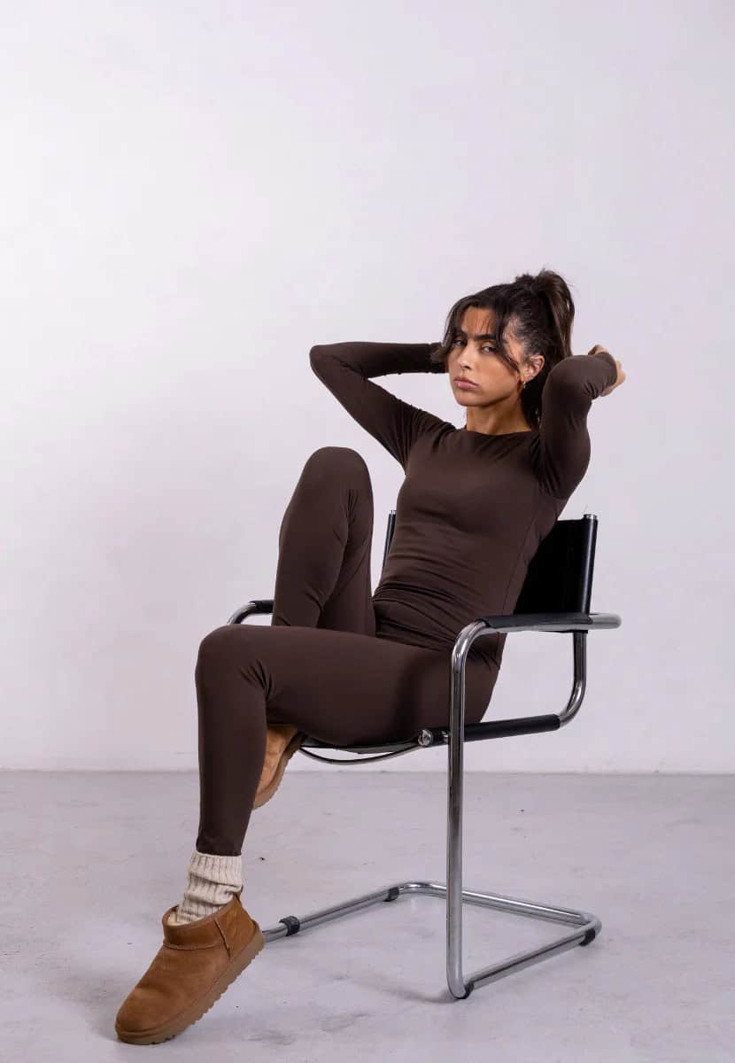 Person sitting on a chair wearing a brown top and leggings from Not Basics