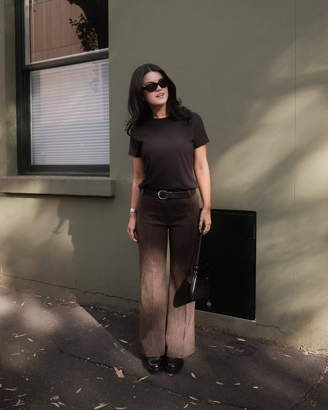 Person wearing a brown t-shirt from Boody and brown trousers.