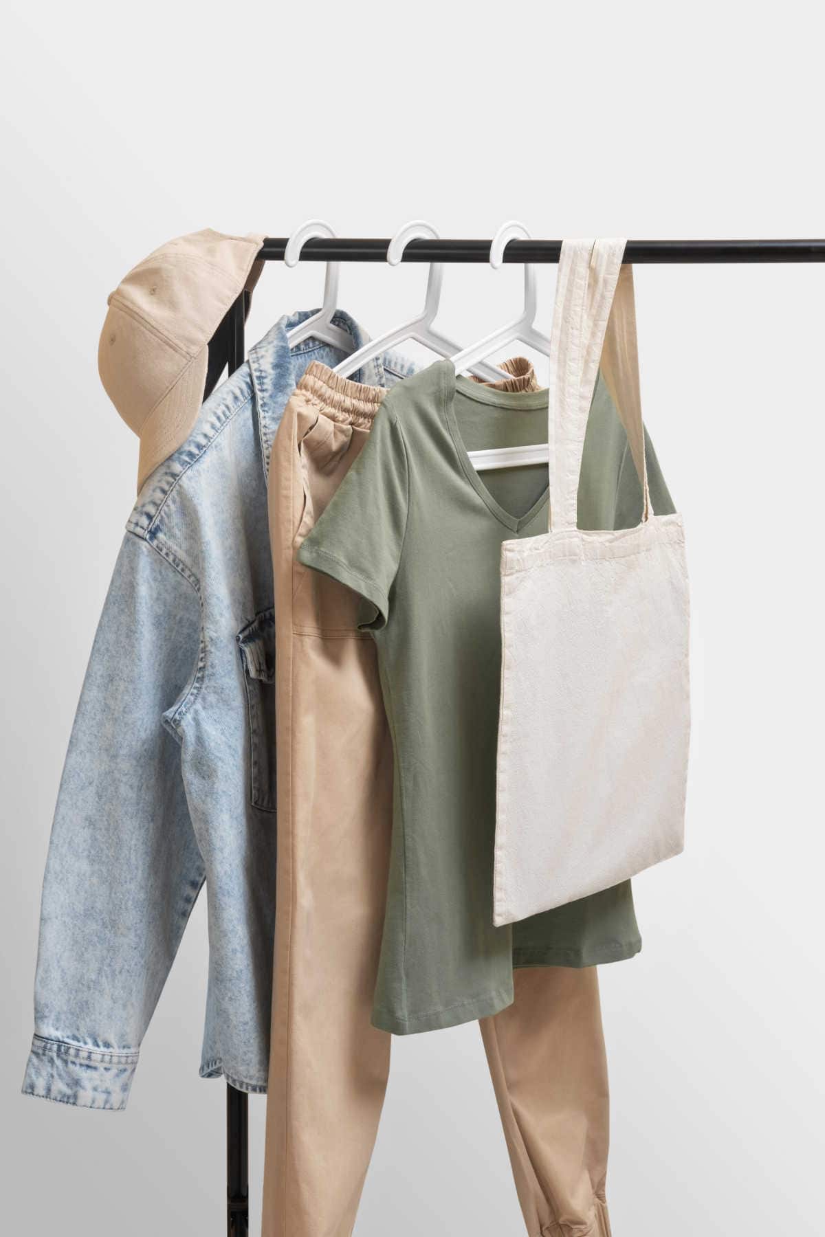 A pair of jeans and some neutral coloured clothing hanging on a rail.