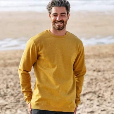 Man wearing a yellow Rapanui recycled cotton sweatshirt - one of the eco-friendly gifts for men featured.