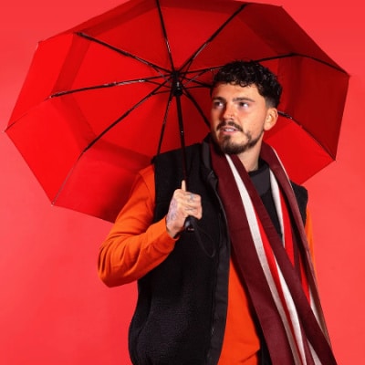 Person holding a red Roka eco-friendly umbrella - made from recycled materials.