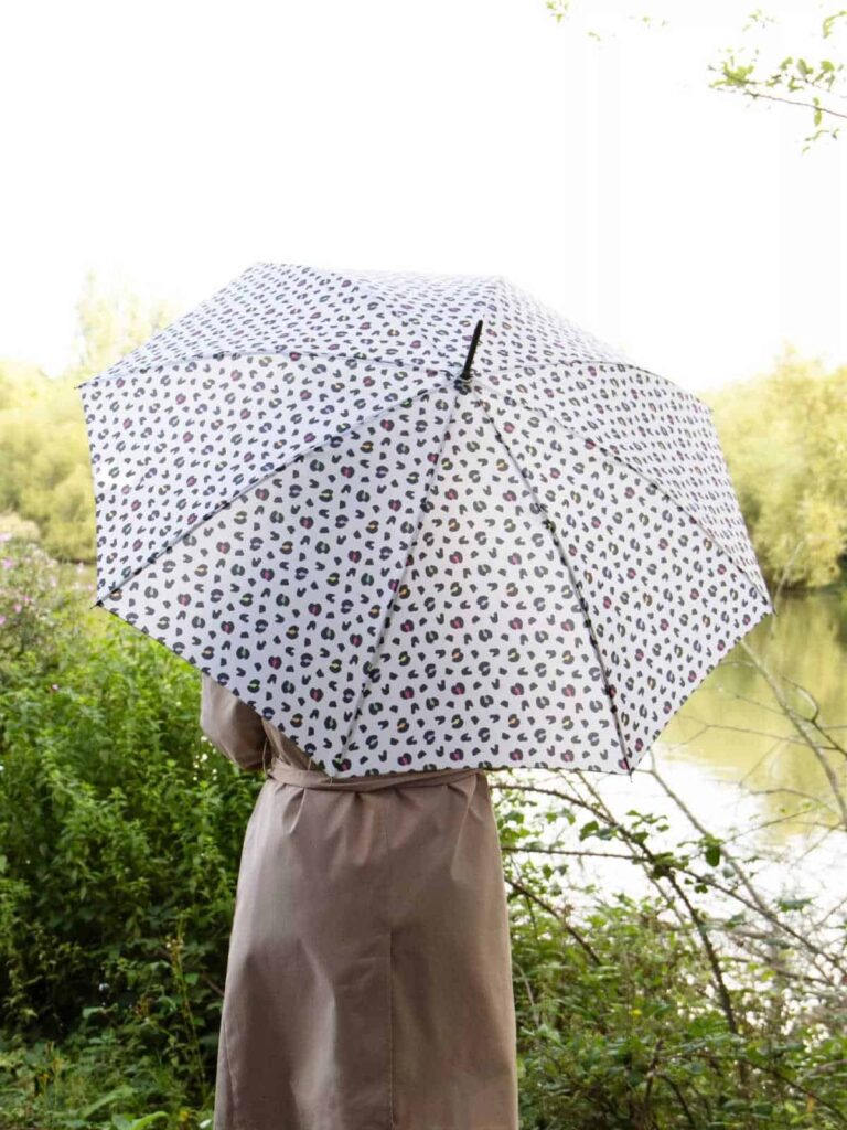 Person holding a Totes eco umbrella made from recycled polyester.