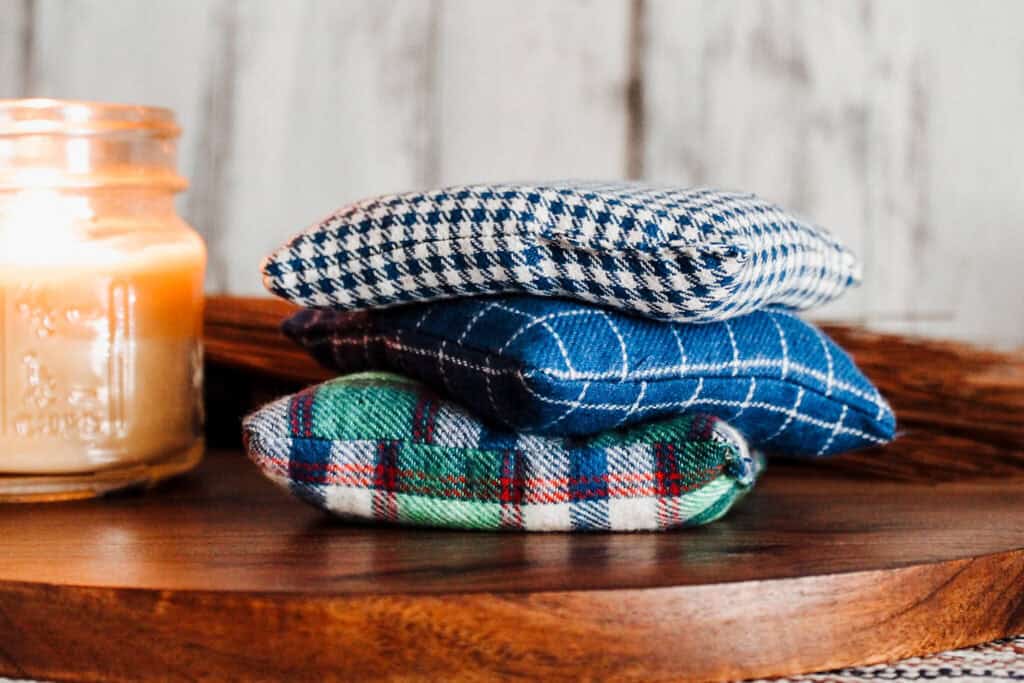 Stack of three checked flannel handwarmers next to a lit candle