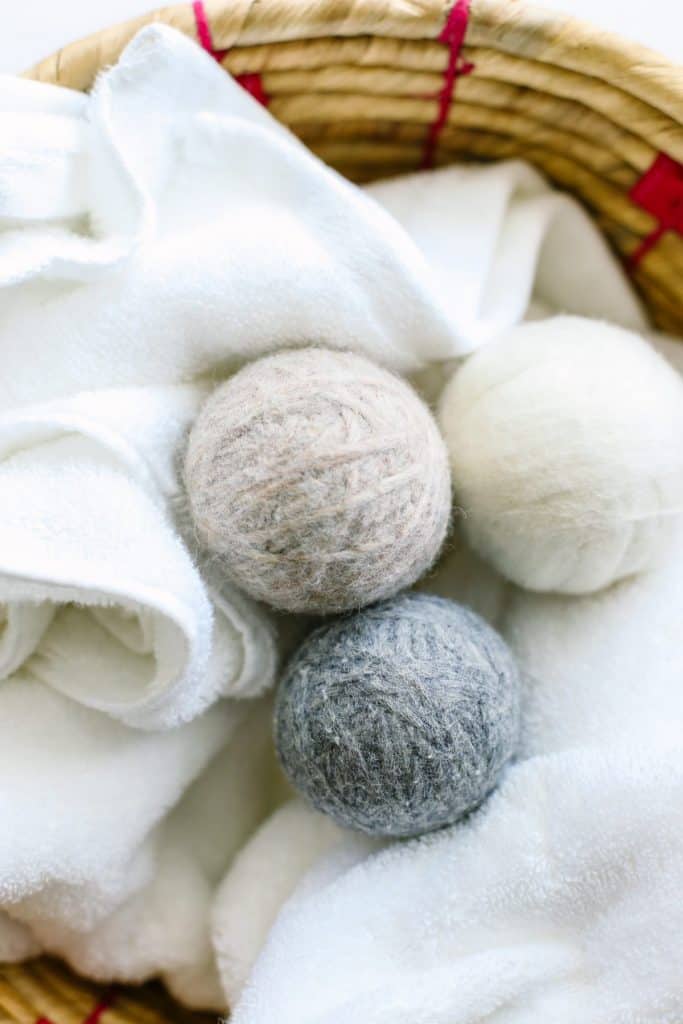 Three homemade dryer balls in a washing basket with white towels.