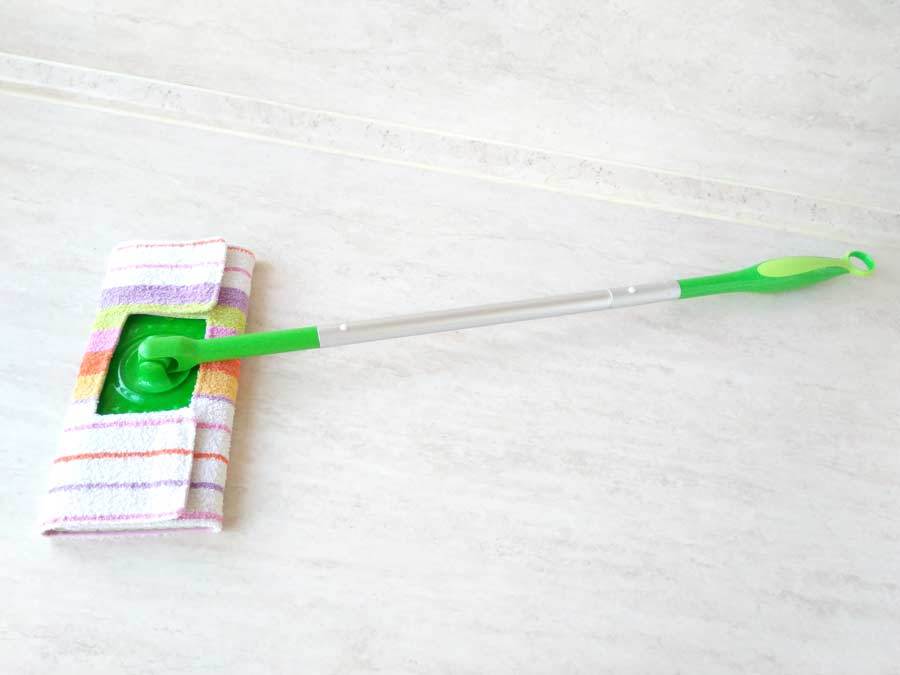 A green handled mop with a homemade mop pad made from an old towel.