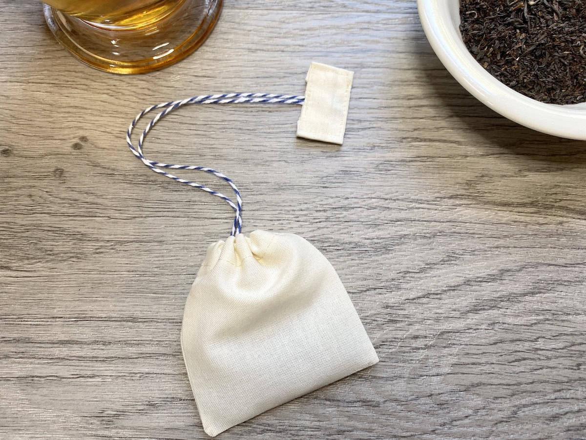 Homemade zero-waste teabag made from muslin and twine, next to various loose tea products.