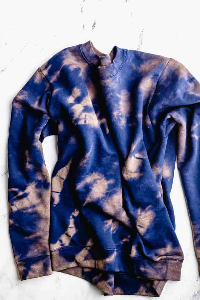 A navy jumper that has had reverse tie-dye with bleach to fix a stain 