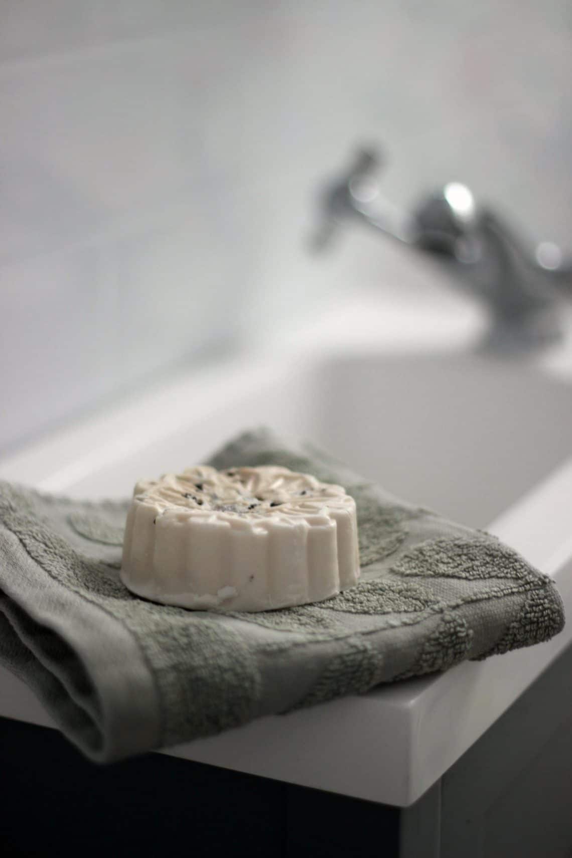 Bar of soap sitting on a folded flannel beside a sink.