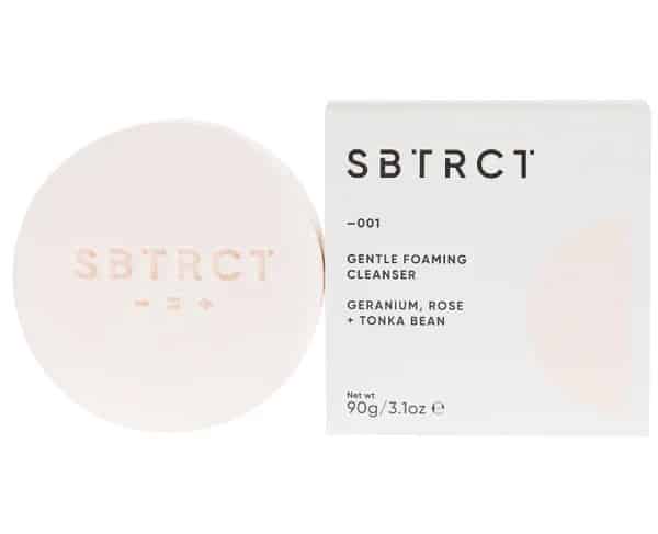 Solid bar of SBTRCT's cleanser next to its cardboard packaging.