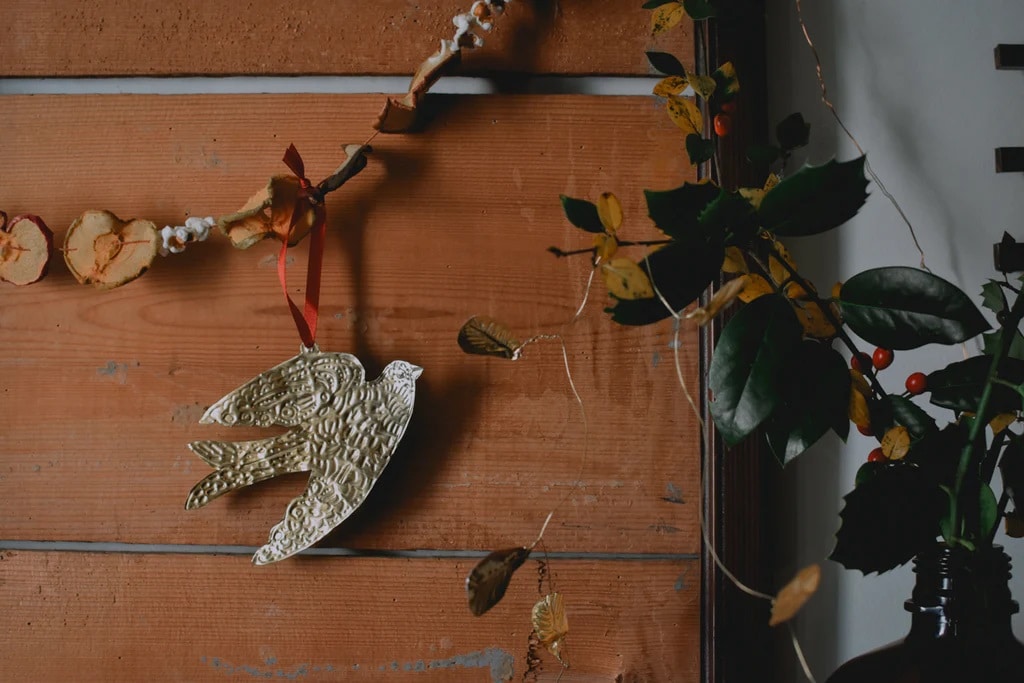 Embossed metal bird decoration made from an old tomato paste tube.